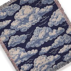 a blue and white blanket with clouds in the sky on it's fringe edge