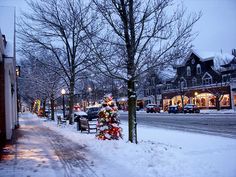 a christmas tree is covered in lights on a snowy street