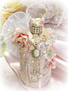 a white vase filled with lots of flowers on top of a pink cloth covered table