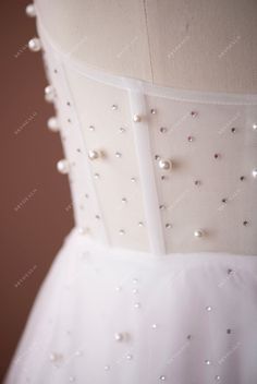 the back of a white wedding dress with pearls on it