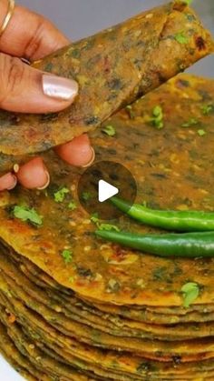 a stack of tortillas being held by a woman's hand with green beans on top