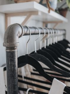 a row of black and white shirts hanging on clothes racks with metal pipe fittings