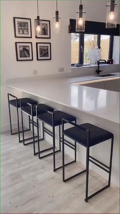 a kitchen island with four stools in front of it and pictures on the wall