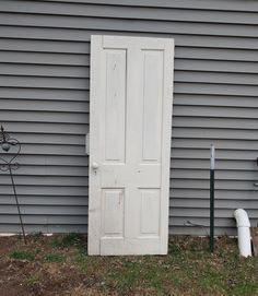 a white door sitting in the grass next to a building