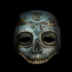 a skeleton mask with ornate designs on it's face and eyes, against a black background