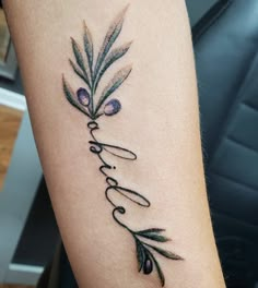 a woman's arm with an olive branch and the word love tattooed on it