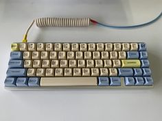 a computer keyboard sitting on top of a white table next to a corded phone