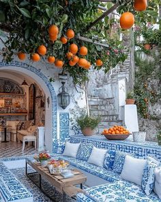 an outdoor seating area with oranges hanging from the ceiling and potted trees in the background