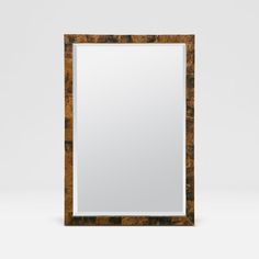 a square mirror sitting on top of a white table next to a black and brown wall