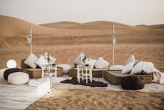 an outdoor seating area in the desert with white cushions and pillows on top of it