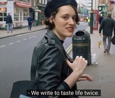 a woman is standing on the side walk with her hand in her pocket and she is holding a mailbox