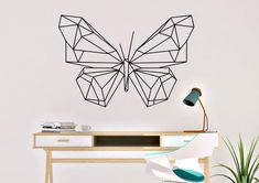 a desk with a chair and a wall mounted butterfly on it's side, next to a potted plant