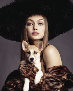 a woman holding a small dog in her arms while wearing a fur coat and hat