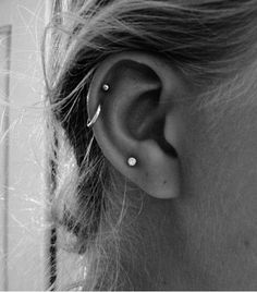 black and white photograph of a woman's ear with two piercings on it