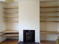 an empty room with some shelves and a fire place in the corner on the floor