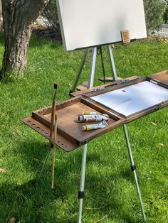 an easel sitting on top of a green grass covered field next to a white board