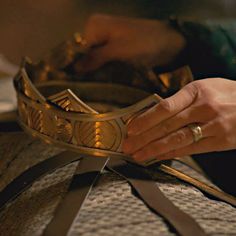 a woman is holding a gold bracelet on top of a table with other items around her