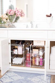 a bathroom sink with lots of items in the cabinet and on top of it is a blue rug