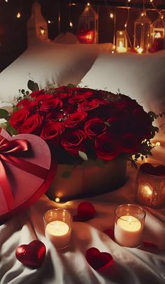 red roses and candles on a bed with white sheets in the background, surrounded by heart - shaped pillows