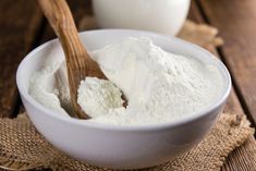 a white bowl filled with powdered sugar next to a wooden spoon