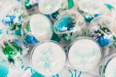 many different colored candies are in plastic containers on a tablecloth with blue and green designs