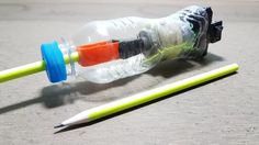 a plastic water bottle with two colored straws next to it and a green pencil