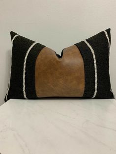 a black and brown pillow sitting on top of a white counter next to a wall