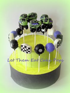 a cake with monster trucks on it and some lollipops in the middle