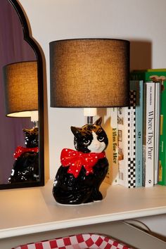 a black and white cat figurine sitting on a shelf next to a lamp