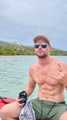 a shirtless man sitting on top of a red boat