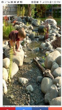 a young boy is playing with rocks in the water at his backyard garden, which has been designed to look like it's made out of stone