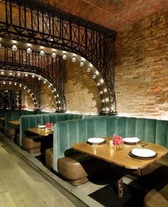 a restaurant with green velvet booths and lights on the ceiling, along with wooden flooring