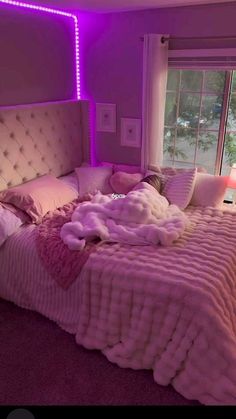 a large bed with pink fur on it in a bedroom next to a purple wall