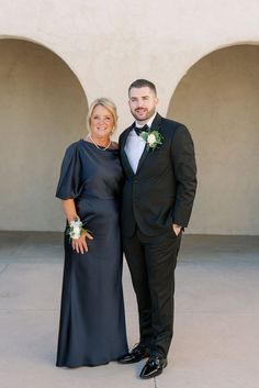 a man and woman in formal wear standing next to each other smiling for the camera