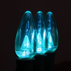 three blue glass vases sitting on top of a black table next to each other