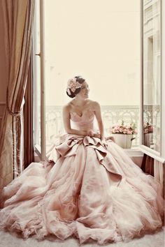 a woman in a ball gown sitting on a window sill