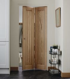 an open wooden door in a white room with black flooring and cabinets on either side