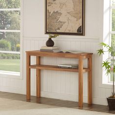 a wooden table sitting in front of a window next to a potted plant on top of a hard wood floor