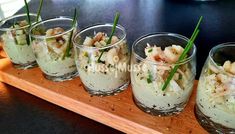 small glasses filled with food sitting on top of a wooden tray