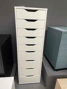 a tall white cabinet sitting on top of a table next to other boxes and drawers