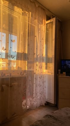 a bedroom with sheer curtains and a television