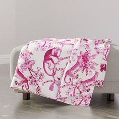 a pink and white blanket sitting on top of a couch next to a gray chair