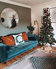 a living room filled with furniture and a christmas tree in front of a round mirror