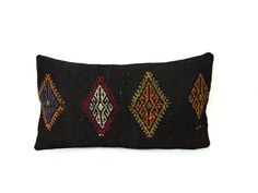 a black pillow with multicolored diamonds on the front and sides, sitting against a white background