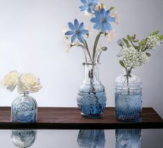 three vases with flowers are sitting on a table