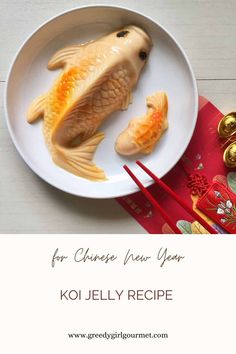 a white plate topped with gold fish next to chopsticks and a red napkin