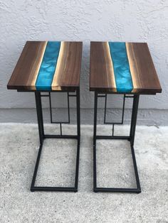 two wooden tables with blue glass in the top and one on each side, against a white wall