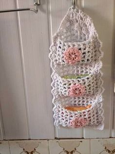 a crocheted wall hanging on the side of a door with flowers in it