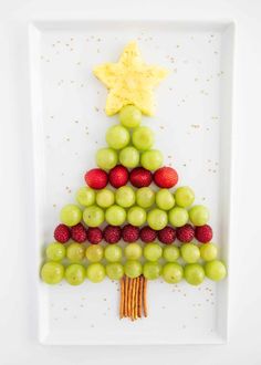 a christmas tree made out of grapes and strawberries on a plate with a star