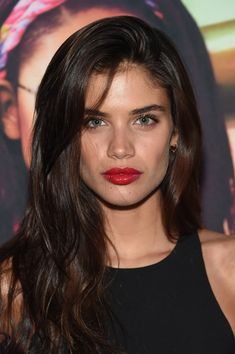 a close up of a person with long hair and dark eyes wearing a black dress